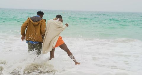 Joyful African American Couple Enjoying Ocean Waves at the Beach