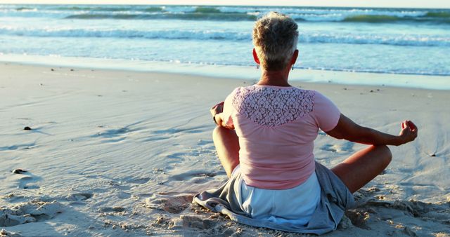A middle-aged individual is practicing meditation on a serene beach at sunset, with copy space. The tranquil setting underscores a moment of mindfulness and relaxation amidst natural beauty.