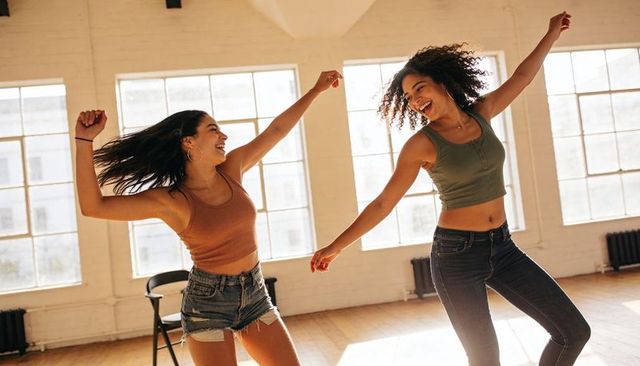Joyful urban dance duo celebrating movement and friendship in sunlit loft studio