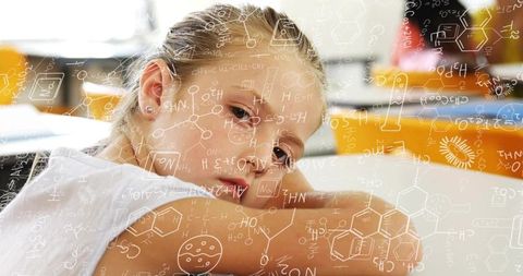 Contemplative schoolgirl resting on desk with overlaid chemistry formulas and soft bokeh
