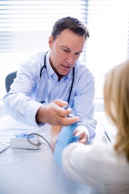 Doctor checking blood pressure of a patient in a clinic. Useful for illustrating medical consultations, healthcare services, and professional medical care. Ideal for health-related articles, medical websites, and educational materials.