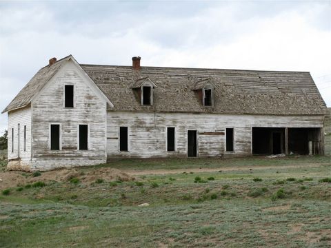 Weathered Abandoned Farmhouse with Peeling White Paint and Broken Windows on Open Prairie