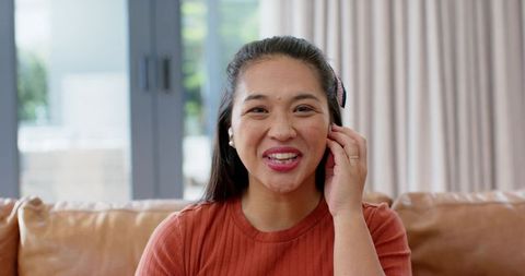 Asian Woman Smiling on Sofa in Cozy Living Room