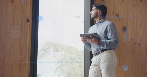 Businessman Standing by Window Holding Tablet in Contemporary Office