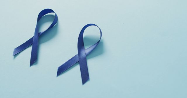 Image of two dark blue colon cancer ribbons on pale blue background. medical and healthcare awareness support campaign symbol for colon cancer.
