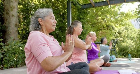 Senior Women Practicing Meditation and Yoga Outdoors on Bright Day