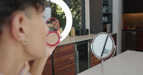 Man applies makeup under led light in modern kitchen