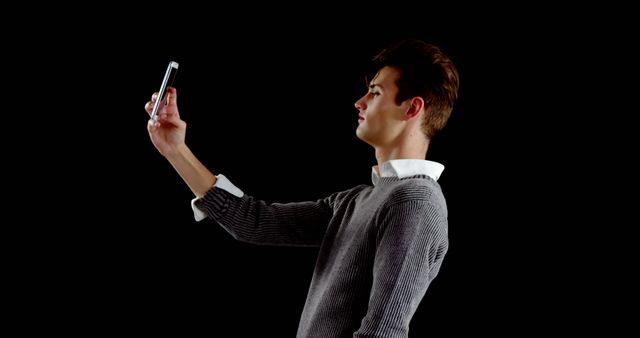 Young Man Taking Selfie on Smartphone Against Black Background - Download Free Stock Images Pikwizard.com