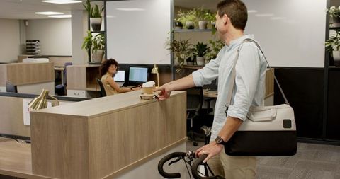 Man offering coffee to receptionist in contemporary office