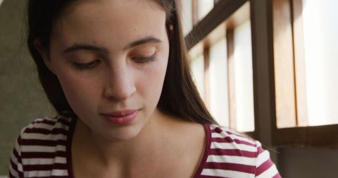 Teenage Girl Focused Playing Ukulele Near Window