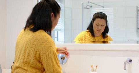 Woman performing morning skincare routine in bathroom