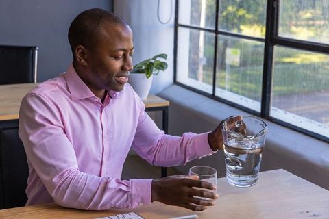 Office Professional Pouring Water from Pitcher in Natural Light