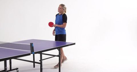 Woman Holding Ping Pong Paddle Near Table in Minimalist Studio