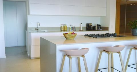 Minimalist kitchen featuring quartz island with apple bowl and cooktop