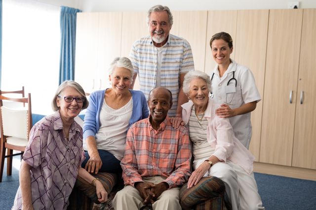 Group of seniors smiling with a caregiver in a nursing home. Ideal for use in healthcare, retirement, and elderly care promotions, showcasing community and support in senior living environments.