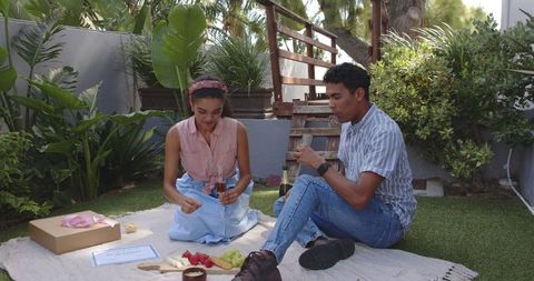 Couple Enjoying Sunny Picnic with Snacks and Drinks Outdoors