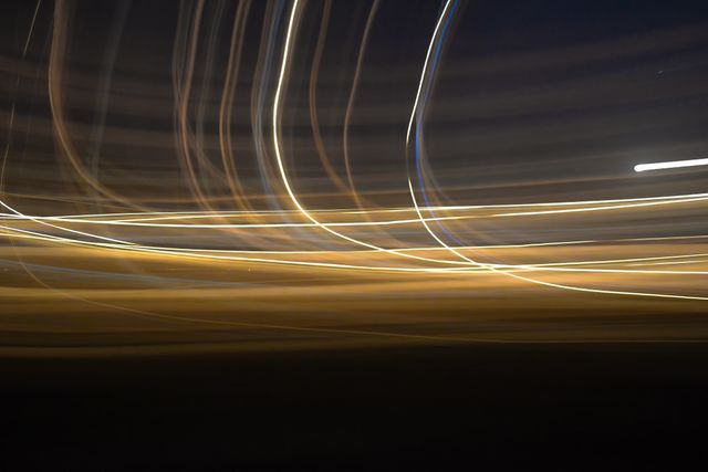 Dynamic visual of light trails captured in motion at night. The long exposure creates streaks of vibrant, glowing lines against a dark background, offering an artistic and abstract aesthetic. This image is ideal for use in creative designs, modern art projects, and backgrounds for visual presentations.