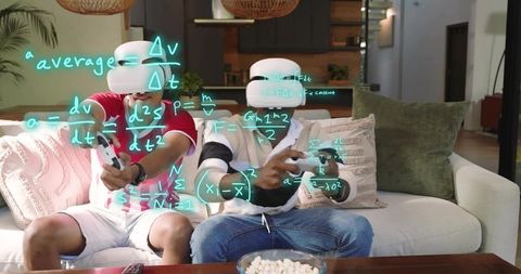 Friends wearing vr headsets racing and solving equations on couch with gamepads
