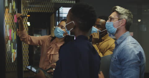 Diverse Team Brainstorming with Face Masks in Modern Office