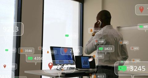 Businessman multitasking at standing desk with phone, laptops, tablet and ar overlays