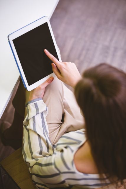 Young female executive using a tablet in an office environment. Ideal for depicting modern business practices, technology in the workplace, and professional women in tech. Suitable for articles on digital transformation, productivity tools, and workplace innovation.