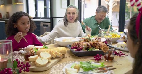 Multigenerational family sharing festive thanksgiving dinner around sunlit wooden table