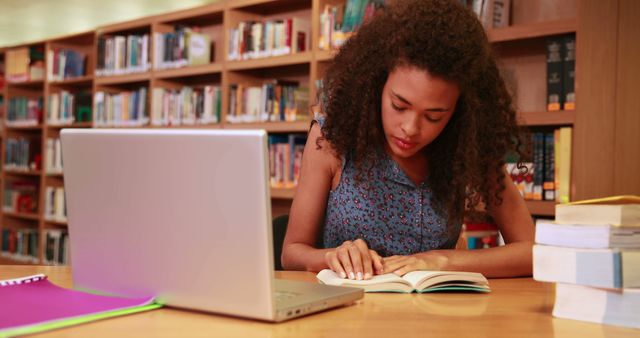 Focused Student Reading Book in Library with Laptop on Desk - Download Free Stock Images Pikwizard.com