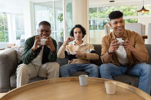 Playing console games together on cozy living room sofa during casual friends game night