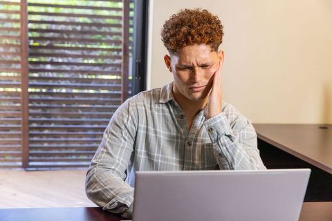 Man Working on Laptop by Window Contemplatively