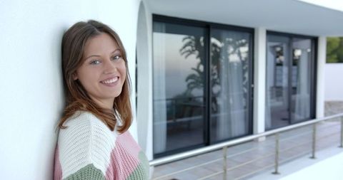 Smiling Woman Relaxing on Modern Balcony with Seaside View