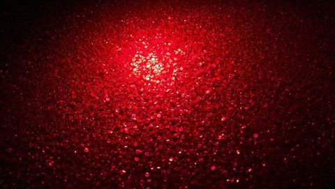 Shimmering crimson sequin texture with bokeh sparkle and bright center glow