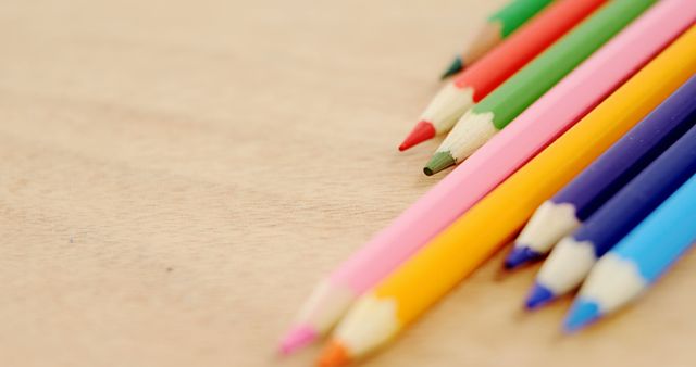 A variety of colored pencils are laid out on a wooden surface, with copy space. Their arrangement suggests a setting of creativity, ideal for art projects or educational activities.