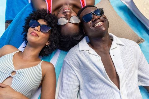 Sunlit summer vibes: african american friends lounging on striped poolside towels