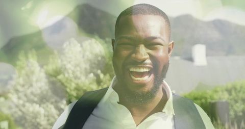 Laughing man outdoors sunlit portrait with bokeh lens flare and lush garden background