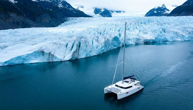 Luxury catamaran cruising along glacier fjord with majestic icefall backdrop