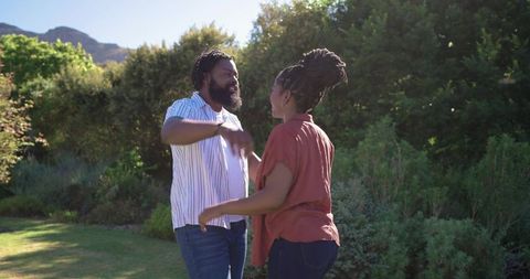 Happy couple reaching for hug in sunlit backyard garden enjoying outdoor togetherness