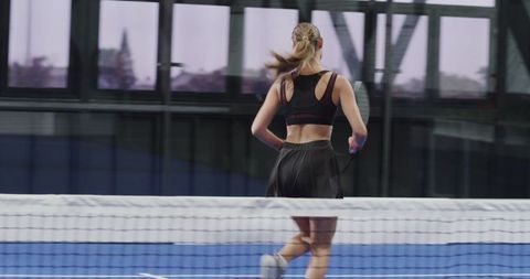 Energetic Young Woman Playing Padel Tennis on Indoor Court