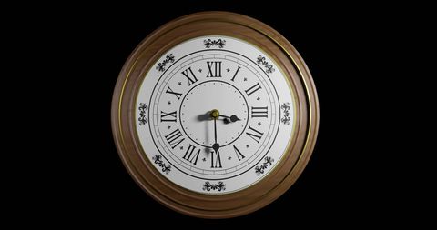 Elegant antique brass clock on black background showing noon