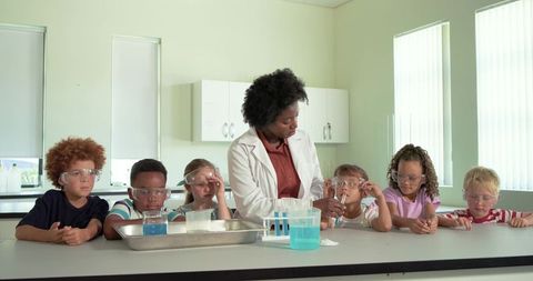 Female teacher leading hands-on science experiment with elementary students in school lab