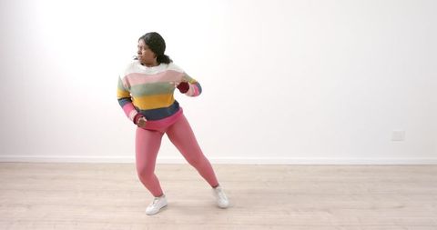 Young woman expressing joyful energy through dance in trendy outfit