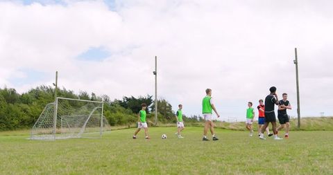 Diverse teen soccer players practicing on green field