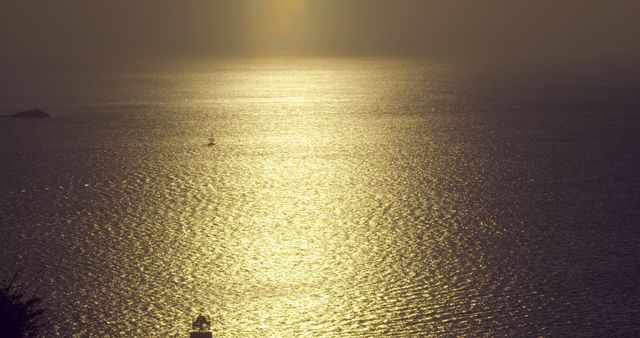 Golden sunlight reflecting off calm ocean water during sunset, exuding a serene and tranquil atmosphere. Perfect for use in travel advertisements, meditation and relaxation content, or inspirational posters.