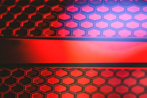 Glowing red honeycomb mesh with horizontal stripe creating futuristic tech pattern