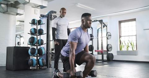 Trainer supervising lunge exercise in gym for fitness training