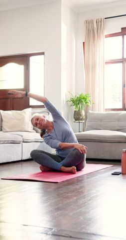 Senior Woman Practicing Yoga Stretching on Pink Mat at Home
