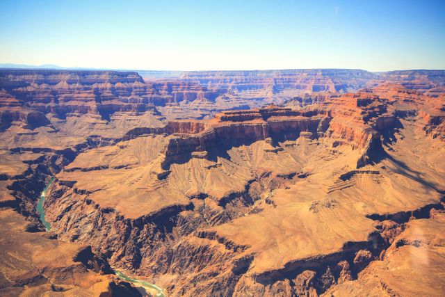 Panoramic aerial view of Grand Canyon revealing its majestic, rocky landscape. Ideal for use in travel brochures, tourism websites, nature blogs, and publications highlighting geological wonders or national parks.