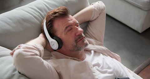 Relaxed man listening to music on sofa with over-ear headphones