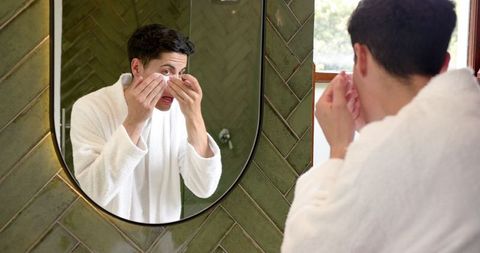 Man in bathroom applying under eye masks