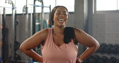 African American woman laughing and standing confidently after strength training in gym