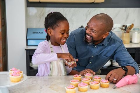 African american father and daughter decorating cupcakes together, laughing, sharing joy